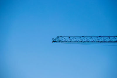 Low angle view of crane against clear blue sky