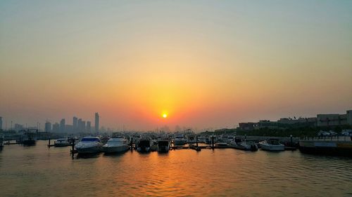 Boats moored in river at sunset