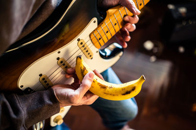 Midsection of man holding guitar