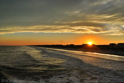 Scenic view of sea against dramatic sky during sunset