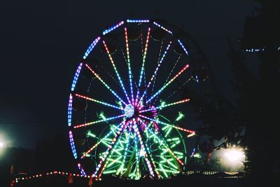 Low angle view of illuminated ferris wheel against sky at night