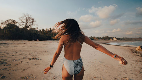 Full length of woman standing on beach against sky