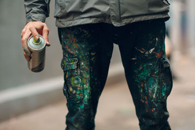 Midsection of man holding aerosol can outdoors