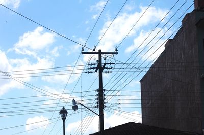 Low angle view of electricity pylons against sky