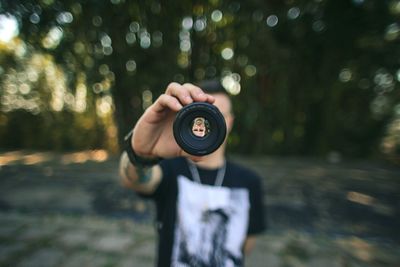 Close-up of woman hand holding camera in forest