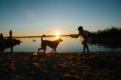 Friends on beach against sky during sunset