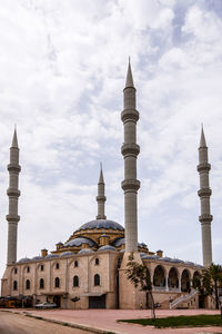 Minarets of a mosque against cloudy sky