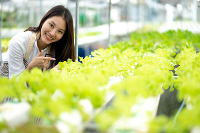 Portrait of young woman standing amidst plants