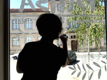 Rear view of man looking through window