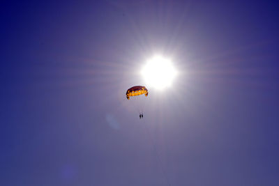 Low angle view of people parasailing against clear sky