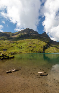 Scenic view of lake by mountain against sky