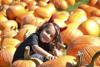 Portrait of cute girl sitting amidst pumpkins