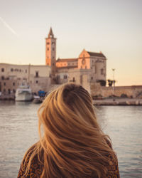 Rear view of woman in canal against sky