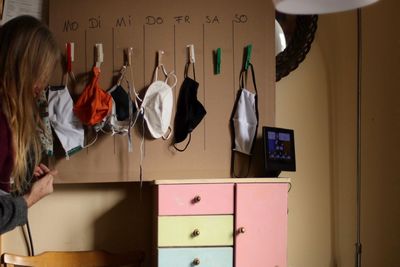 Midsection of woman standing against masks at home