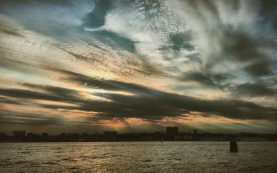 Scenic view of sea against cloudy sky at sunset