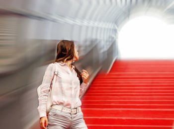 Woman looking away while standing on red steps