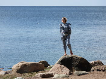 Woman standing on rock looking at sea shore