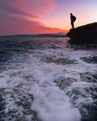 Silhouette man surfing in sea against sky during sunset