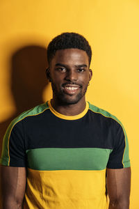 Portrait of young man standing against yellow background