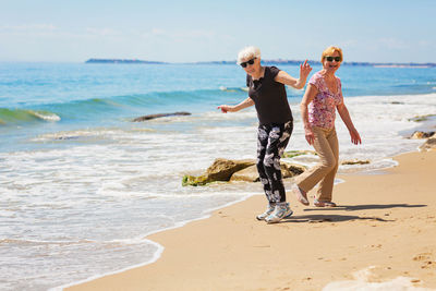 Two elderly women walking along the rocky seashore