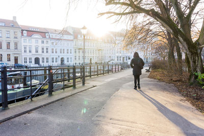 Rear view of woman walking on promenade in city during sunny day