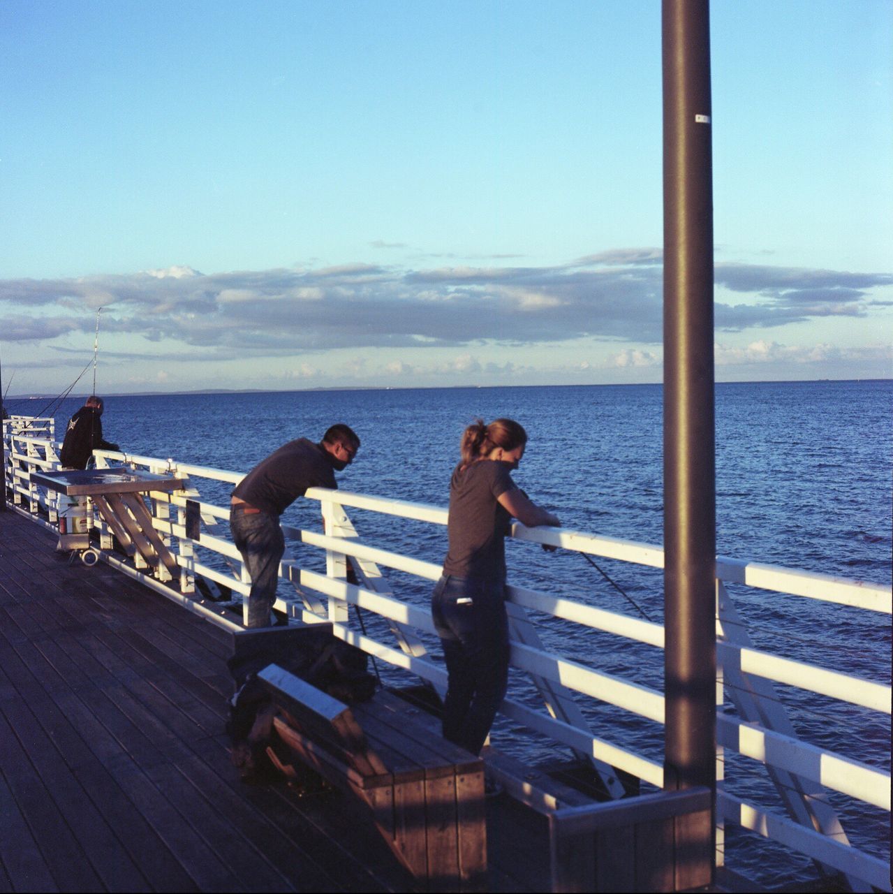 railing, sea, sky, water, full length, leisure activity, day, wood - material, nature, outdoors, blue, togetherness, standing, two people, men, beauty in nature, nautical vessel, real people, horizon over water, adult, people