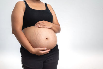 Midsection of woman touching face against white background