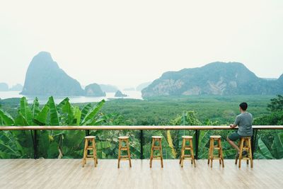 Rear view of man looking at mountains against clear sky