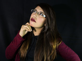 Close-up of young woman against black background