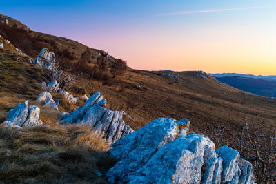 Panoramic view of rocks and mountain against sky during sunset