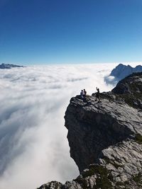 Friends on cliff against sky