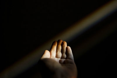 Close-up of person hand against black background