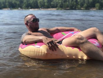 Man sitting on inflatable ring on lake