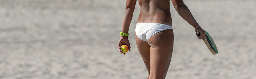 Low section of man with umbrella on beach