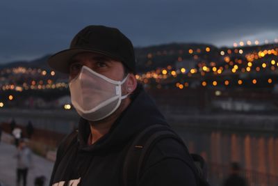 Young man wearing mask looking away at night