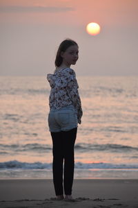 Full length of woman standing on beach during sunset