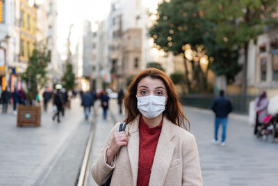 Portrait of woman wearing mask standing on city street