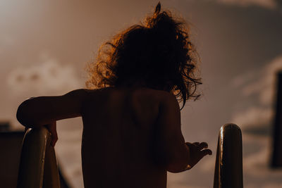 Rear view of girl against sky during sunset