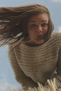 Portrait of young woman making a face against sky