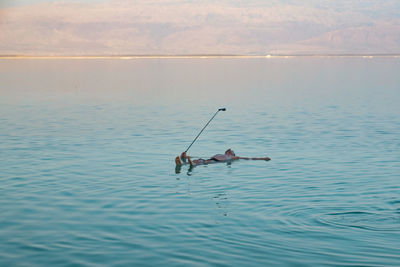 People fishing in sea against sky