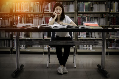 Portrait of young woman sitting on book