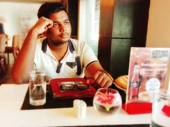 Portrait of young man sitting at restaurant table