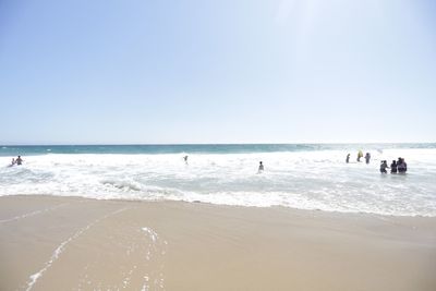 People enjoying in sea against clear sky