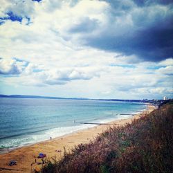 Scenic view of beach against cloudy sky