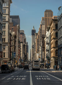 Vehicles on road in city against sky