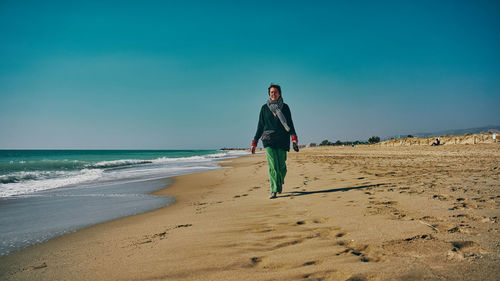 Senior woman walks along the beach on a sunny day