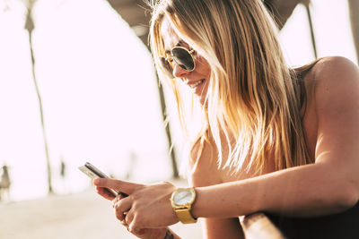 Young woman using mobile phone sitting outdoors