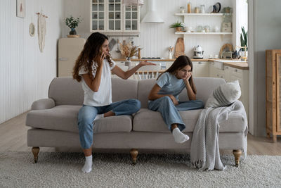 Side view of woman using phone while sitting on sofa at home