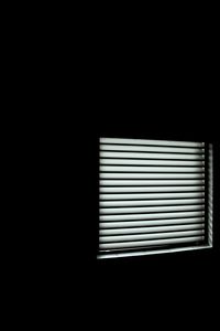 Close-up of window blinds against black background