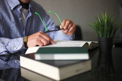 Midsection of man reading book on table